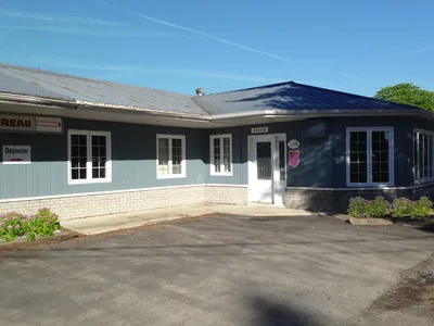 Vue extérieure de l’entrée du motel avec son revêtement bleu et ses fenêtres à carreaux blancs.
