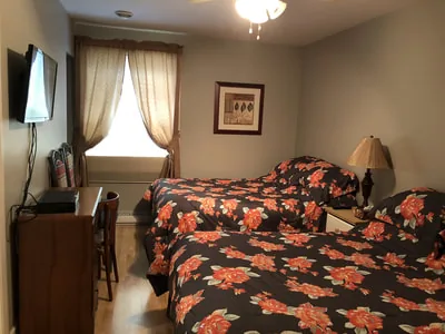 Une chambre de motel avec deux lits, mobilier en bois et fenêtre éclairée.